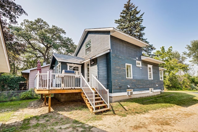 back of property with a deck and a lawn