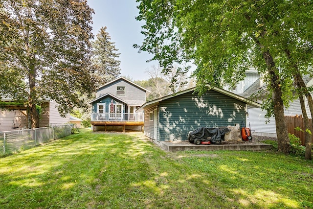 rear view of house featuring a lawn and a wooden deck