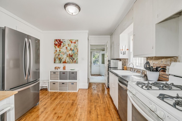 kitchen with sink, white cabinetry, stainless steel appliances, light wood-type flooring, and crown molding