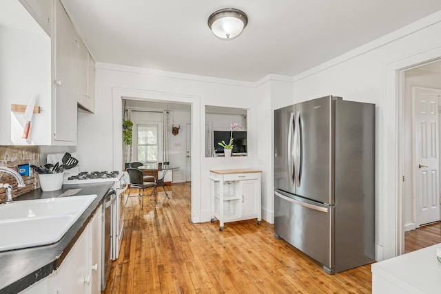 kitchen featuring stainless steel appliances, white cabinets, light hardwood / wood-style floors, and sink