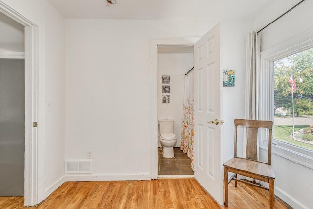 bedroom with connected bathroom and light hardwood / wood-style floors