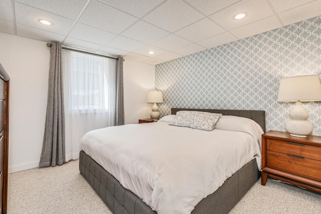 bedroom with a drop ceiling and light colored carpet