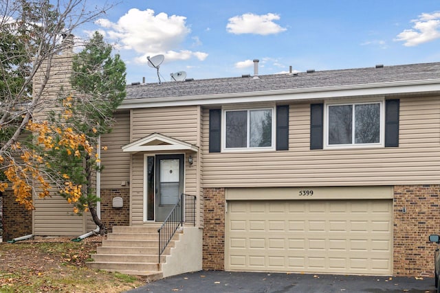 view of front of property with aphalt driveway, entry steps, brick siding, and a garage