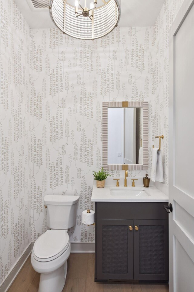 bathroom featuring vanity, toilet, an inviting chandelier, and hardwood / wood-style flooring