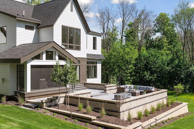 rear view of property with an outdoor living space with a fire pit and a lawn