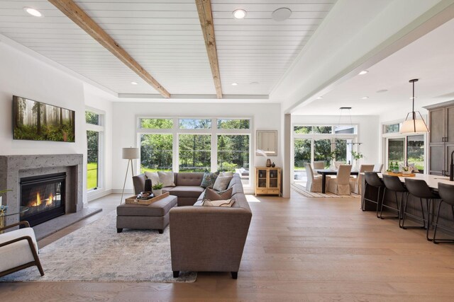 living room featuring a premium fireplace, light wood-type flooring, and beam ceiling