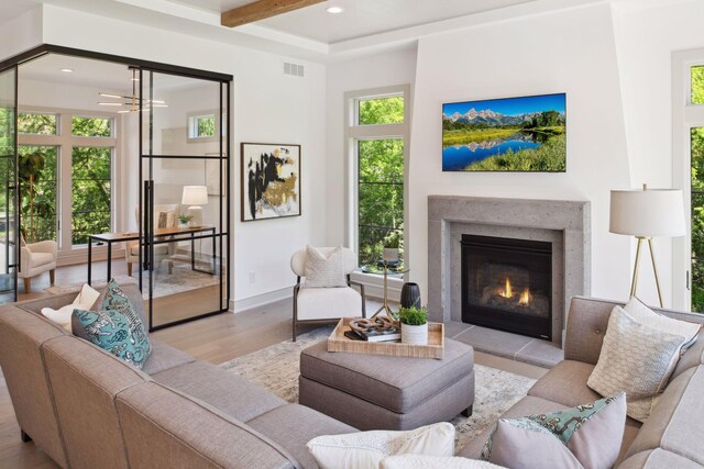 living room with a wealth of natural light, beamed ceiling, and light hardwood / wood-style floors