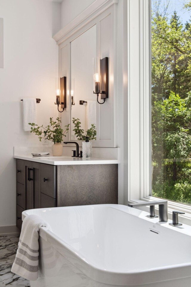 bathroom featuring vanity, a bath, and a healthy amount of sunlight