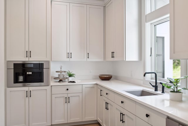 kitchen with sink, oven, and white cabinets