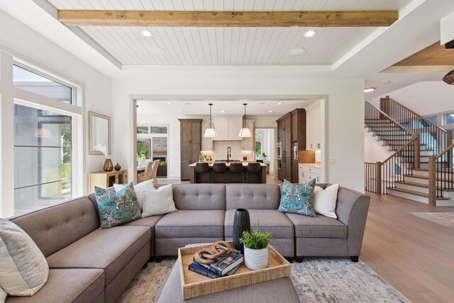 living room with beam ceiling, sink, light wood-type flooring, and wooden ceiling