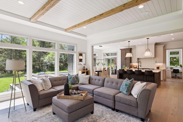 living room with light wood-type flooring, a wealth of natural light, beam ceiling, and wooden ceiling