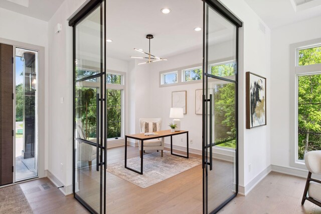 office area featuring light wood-type flooring, french doors, and a healthy amount of sunlight