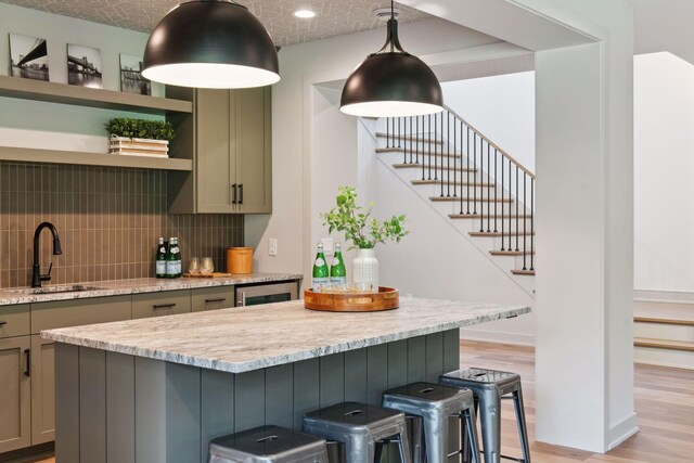 kitchen featuring a breakfast bar, light wood-type flooring, sink, and decorative backsplash