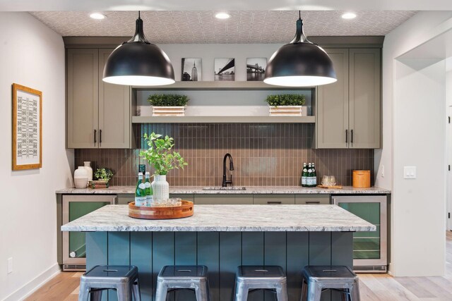 kitchen with a kitchen breakfast bar, beverage cooler, sink, and tasteful backsplash