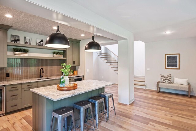 kitchen with a kitchen island, a breakfast bar area, light hardwood / wood-style flooring, sink, and decorative backsplash