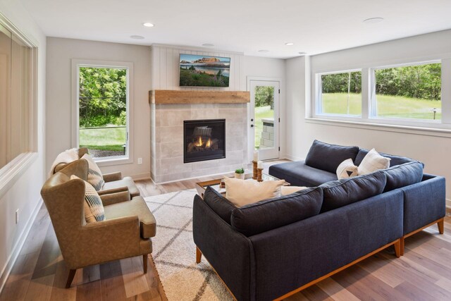 living room featuring hardwood / wood-style flooring, a tiled fireplace, and a healthy amount of sunlight