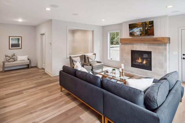 living room featuring light wood-type flooring and a tiled fireplace