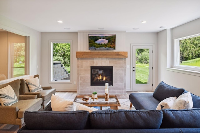 living room with plenty of natural light, a tiled fireplace, and light wood-type flooring