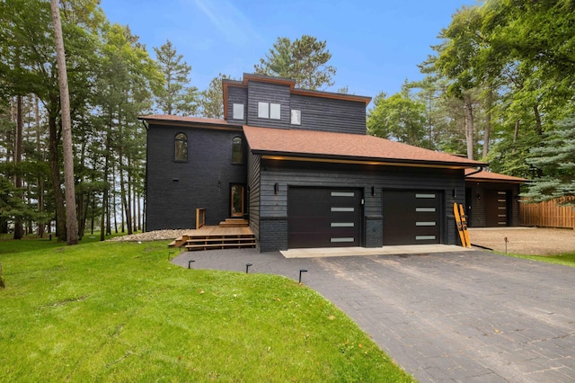 contemporary house with a front lawn, a deck, and a garage