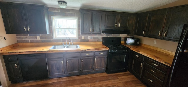 kitchen featuring butcher block countertops, a sink, under cabinet range hood, and black appliances