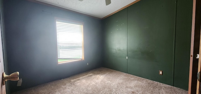 spare room with crown molding, a ceiling fan, a textured ceiling, and carpet flooring