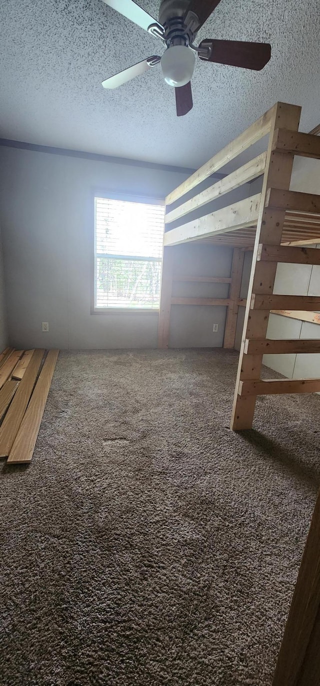 unfurnished bedroom featuring carpet floors, a ceiling fan, and a textured ceiling