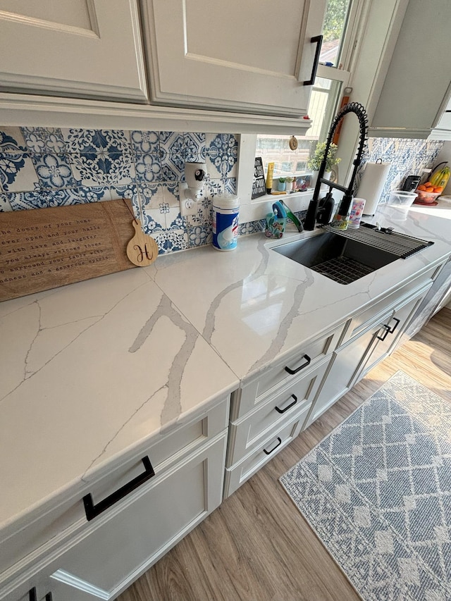 details featuring a sink, light stone countertops, and light wood-type flooring