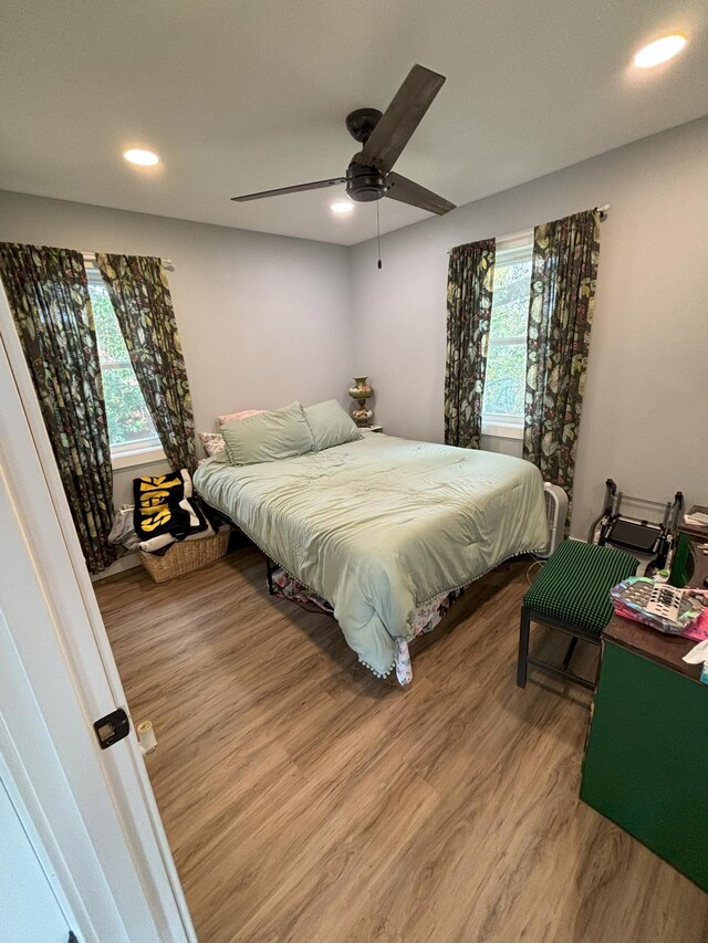 bedroom with ceiling fan, hardwood / wood-style flooring, and multiple windows