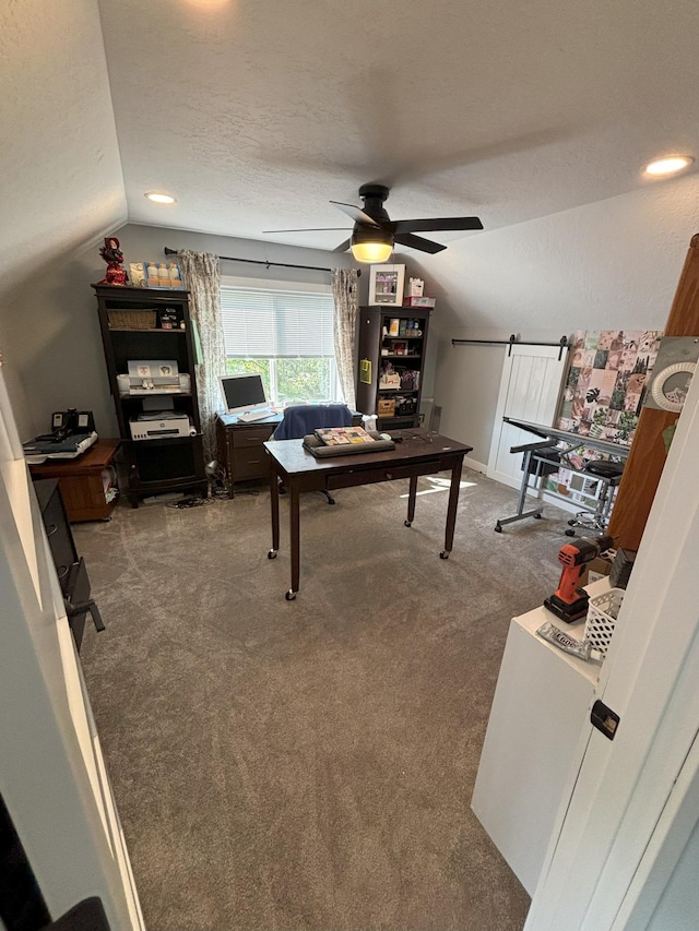 playroom featuring ceiling fan, lofted ceiling, a textured ceiling, carpet, and a barn door