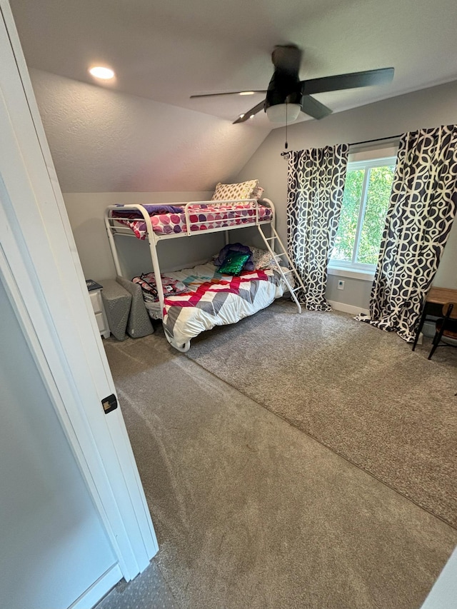 carpeted bedroom featuring lofted ceiling, ceiling fan, and a textured ceiling