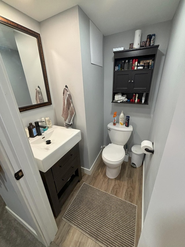 bathroom featuring vanity, baseboards, wood finished floors, and toilet