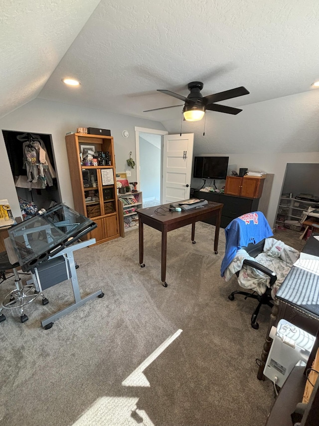 carpeted home office featuring a textured ceiling, vaulted ceiling, and ceiling fan