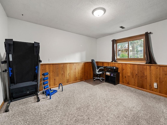 office featuring a textured ceiling, light colored carpet, and wooden walls