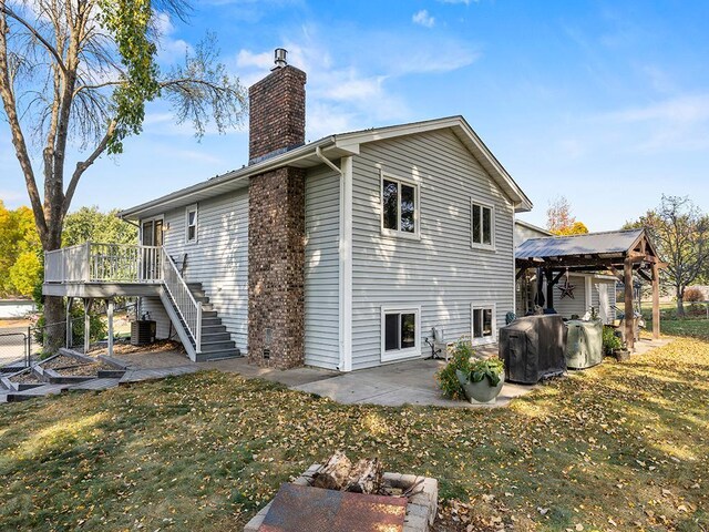 rear view of house featuring a wooden deck, a yard, central air condition unit, and a patio area