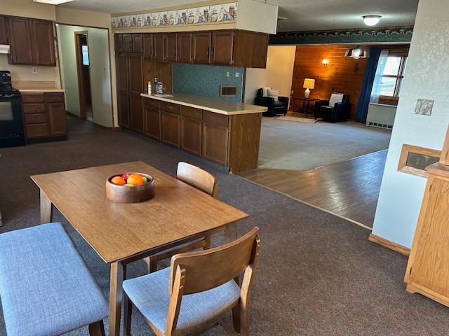 dining area featuring dark colored carpet and wooden walls