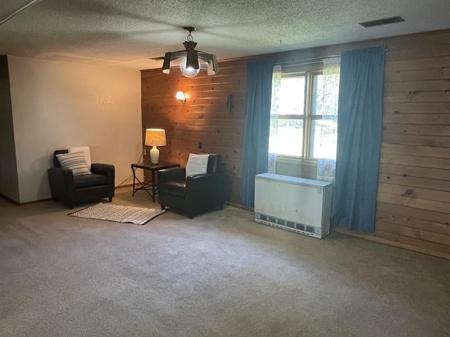 unfurnished room featuring carpet floors, wooden walls, heating unit, and a textured ceiling