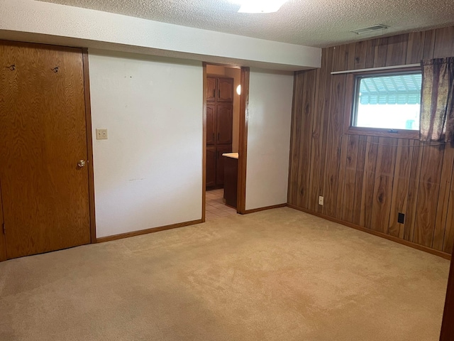 interior space with wooden walls, light carpet, and a textured ceiling