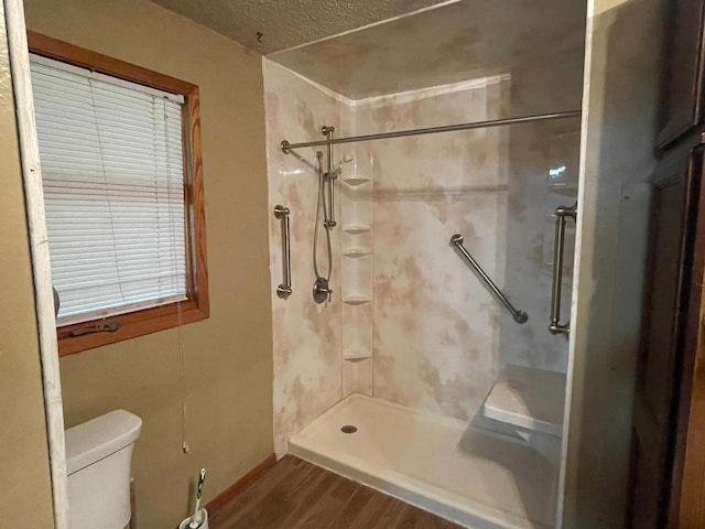 bathroom with hardwood / wood-style flooring, tiled shower, toilet, and a textured ceiling