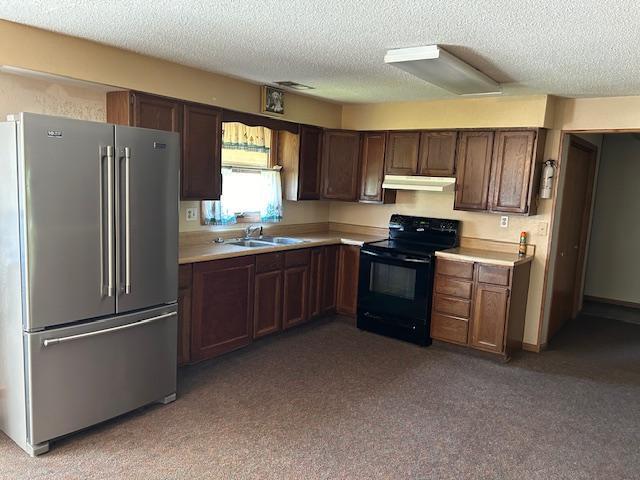 kitchen with high end fridge, black range with electric stovetop, sink, and a textured ceiling