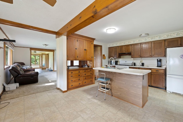 kitchen featuring open floor plan, beamed ceiling, freestanding refrigerator, light countertops, and a sink