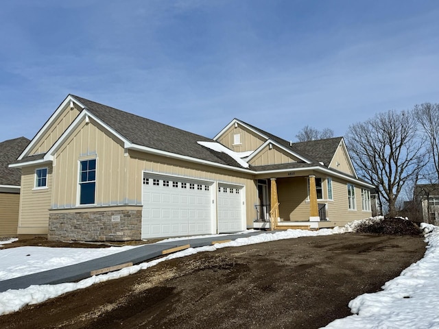 craftsman-style house featuring driveway, stone siding, roof with shingles, board and batten siding, and a garage