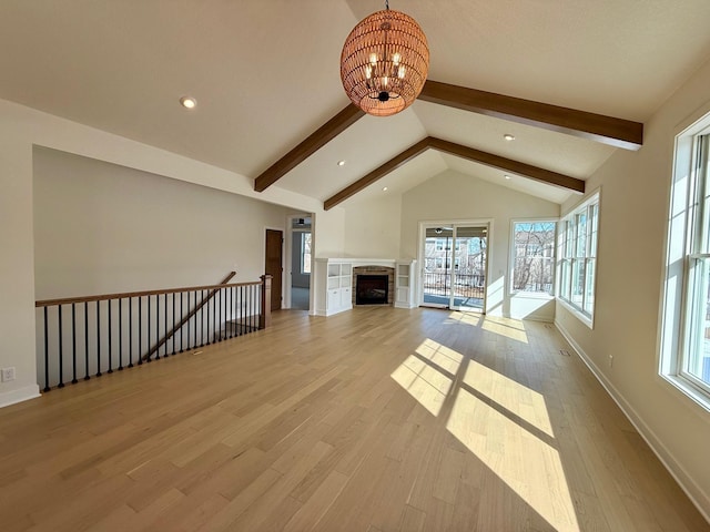 unfurnished living room with wood finished floors, a fireplace, baseboards, a chandelier, and vaulted ceiling with beams