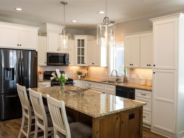 kitchen with white cabinets, a center island, dark hardwood / wood-style flooring, sink, and black appliances