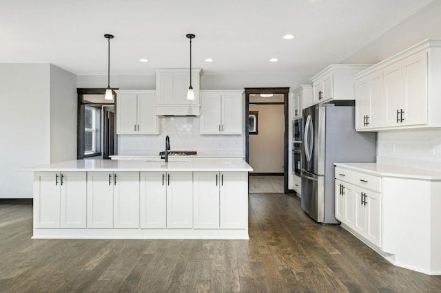 kitchen featuring hanging light fixtures, white cabinets, dark hardwood / wood-style flooring, and a kitchen island with sink