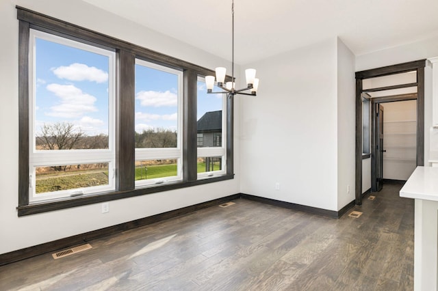 unfurnished dining area with an inviting chandelier and dark hardwood / wood-style flooring