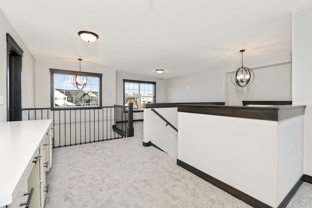 kitchen with hanging light fixtures, white cabinetry, a chandelier, and light carpet