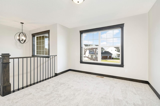 spare room with a chandelier and carpet flooring