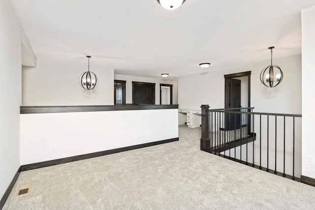 carpeted spare room featuring an inviting chandelier