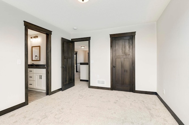 unfurnished bedroom featuring ensuite bathroom and light colored carpet