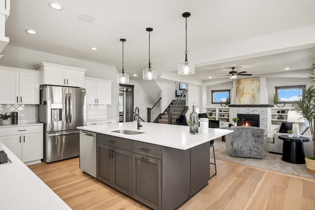 1105 136th St E, Rosemount, MN 55068 - kitchen featuring stainless steel appliances, a sink, white cabinets, a stone fireplace, and light countertops